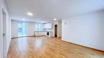 Helles, offenes Wohnzimmer mit integrierter Küche, Holzboden und Zugang zu einem Außenbereich.