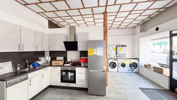 Geräumiger Raum mit einer Einbauküche, Haushaltsgeräten und einem dekorativen Holzgitter an der Decke.