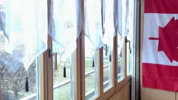 Heller Wintergarten mit vielen Fenstern, Holzverkleidung und Blick auf die umliegende Natur.