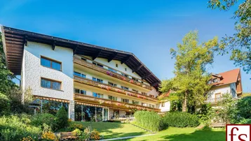 Großzügiges Anwesen mit gepflegtem Garten, Balkonen und traditioneller Architektur, umgeben von viel Grün.