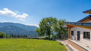 Großer Rasenbereich mit Bäumen und einem atemberaubenden Panoramablick auf die umliegende Berglandschaft.