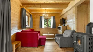 Rustikales Wohnzimmer mit Holzboden, Kaminofen und bequemen Sitzgelegenheiten.