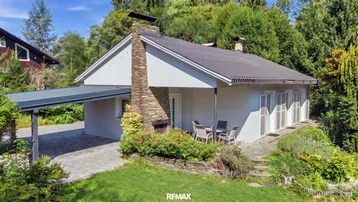 Haus mit Terrasse, Carport und Garten in grüner Umgebung, ideal zum Entspannen.