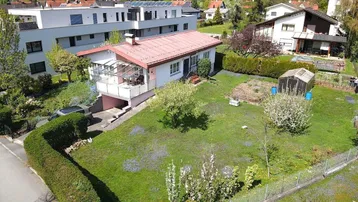 Luftaufnahme eines Einfamilienhauses mit großem Garten, Gewächshaus und umliegender Wohnbebauung.
