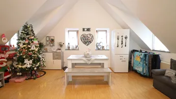 Geräumiger Wohn- und Essbereich im Dachgeschoss mit schrägen Wänden, Holzboden und festlicher Weihnachtsdekoration.