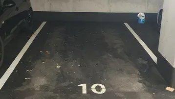 Leerer Parkplatz Nummer 10 in einer Tiefgarage mit Betonwänden und dunklem Boden.