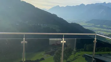 Großer Balkon mit Glasgeländer und atemberaubendem Panoramablick auf die umliegende Bergwelt.