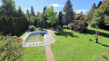 Weitläufiger Garten mit Rasenflächen, altem Baumbestand und einem vorbereiteten Poolbereich.