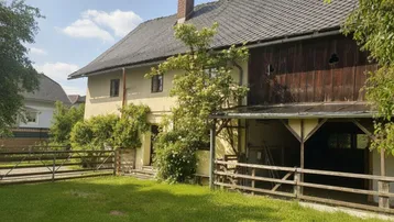 Ansicht des historischen Gebäudes mit großem Gartenbereich und Holzverkleidung unter dem Dach.