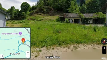 Überwuchertes Grundstück mit baufälligen Gebäuden und hügeliger Landschaft im Hintergrund, inklusive Kartenausschnitt.