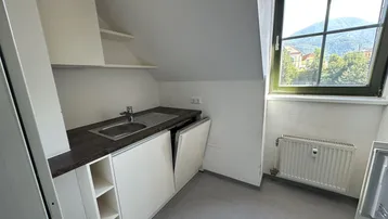Kompakte Küchenzeile mit Spüle, Stauraum und Blick aus dem Fenster in die Berglandschaft.