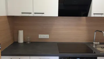 Moderne Einbauküche mit weißen Schränken, Induktionskochfeld und integriertem Backofen.