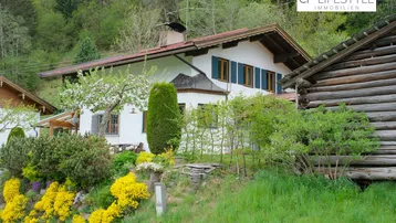 Traditionelles Haus im alpinen Stil mit gepflegtem Garten und grüner Umgebung.
