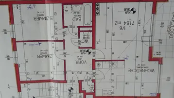 Grundriss einer Wohnung mit offener Wohnküche, zwei Zimmern, Bad, separatem WC und Balkon.