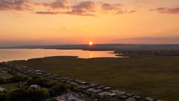 Panoramablick auf die Wohnanlage bei Sonnenuntergang mit See und weitem Landblick.