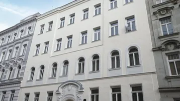 Die frisch renovierte Fassade des Altbaus mit vielen Fenstern und klassischer Architektur.