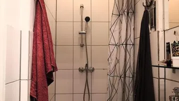 Kleines Badezimmer mit Duschbereich, Waschbecken und Spiegel, funktional eingerichtet.