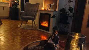 Gemütliches Wohnzimmer mit Parkettboden, Kamin und stimmungsvoller Beleuchtung am Abend.