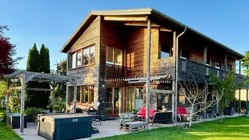 Großzügiger Gartenbereich mit Holzhaus, Terrasse, Whirlpool und Pergola, ideal für Entspannung im Freien.