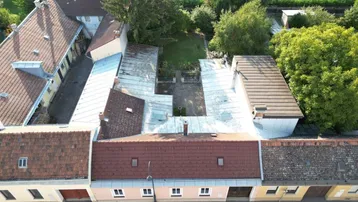 Luftaufnahme von Gebäuden mit roten Ziegeldächern und einem Innenhofbereich.