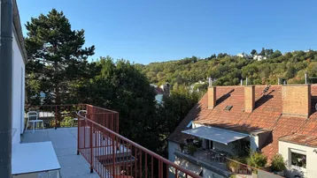 Geräumige Terrasse mit Fliesenboden, rotem Geländer und weitem Blick ins Grüne.