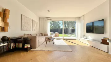 Helles Wohnzimmer mit modernem Sofa, Holzboden und direktem Zugang zum gepflegten Garten.