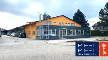 Außenansicht eines modernen Gewerbegebäudes mit orangefarbener Fassade, großen Fenstern und Parkplätzen.