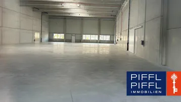 Große, leere Lagerhalle mit hohen Decken und Betonwänden, ideal für gewerbliche Nutzung und Lagerung.