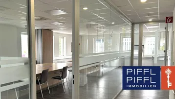Moderner Bürobereich mit Glaswänden, der einen Konferenzraum und einen Flur verbindet und viel Tageslicht bietet.