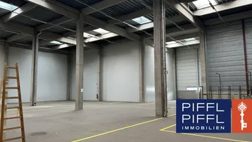 Geräumige, leere Lagerhalle mit hohen Decken, Betonstützen und Oberlichtern, bereit zur Nutzung.