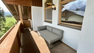 Gemütlicher Balkon mit Sitzgelegenheit und weitem Blick auf die grüne Landschaft und Berge.