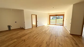 Helles, geräumiges Wohnzimmer mit Holzboden und Zugang zu einem Balkon, bereit zur Einrichtung.