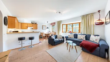 Geräumiger offener Wohn- und Essbereich mit Holzboden, gemütlichen Sofas und integrierter Küche.