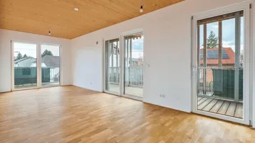 Helles Wohnzimmer mit Holzboden, Holzdecke und Zugang zu mehreren Balkonen.