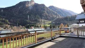 Geräumige Terrasse mit Fliesenboden und Holzbalkongeländer, bietet einen weiten Blick auf die Berge.