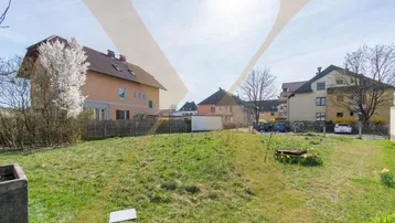 Großes Grundstück mit Rasenfläche und umliegenden Wohnhäusern unter blauem Himmel.