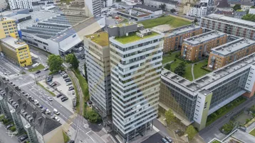Luftaufnahme eines modernen Bürokomplexes mit begrünten Dächern in städtischer Umgebung.