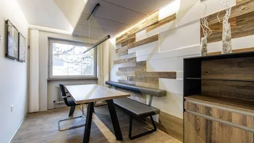 Moderner Essbereich mit Holzwandverkleidung, langer Sitzbank und großem Fenster für natürliches Licht.