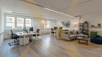 Heller und modern eingerichteter Büroraum mit Arbeitsplätzen und gemütlicher Lounge-Ecke.