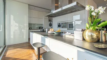 Elegante moderne Küche mit weißen Schränken, dunkler Arbeitsplatte und integrierten Geräten.