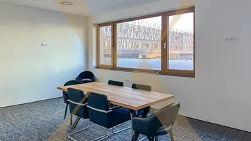 Moderner Konferenzraum mit Holztisch, bequemen Stühlen und Blick auf die Umgebung.