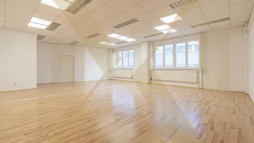 Geräumiges, leeres Büro mit hellem Laminatboden und großen Fenstern, ideal für verschiedene Geschäftsnutzungen.