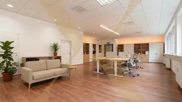 Helles und geräumiges Büro mit modernen Möbeln, Holzboden und großen Fenstern, ideal für produktives Arbeiten.