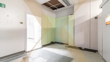 Geräumiger Innenraum mit abgehängter Decke und sichtbaren Lüftungskanälen, teilweise renoviert.