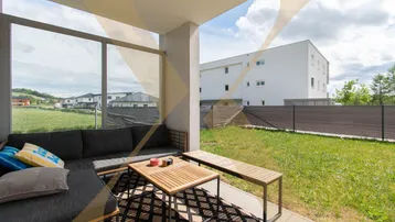 Überdachte Terrasse mit gemütlicher Lounge-Sitzgruppe und Blick ins Grüne.