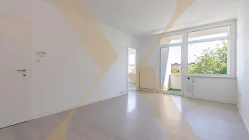 Helles Wohnzimmer mit modernem Laminatboden, weißen Wänden und Zugang zu einem kleinen Balkon.