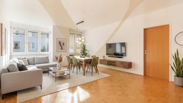 Heller Wohn-Essbereich mit modernem Sofa, Esstisch und Parkettboden, ideal für geselliges Beisammensein.