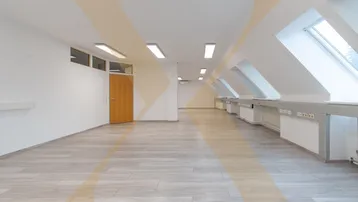 Geräumiger Büroraum im Dachgeschoss mit schrägen Wänden, Dachfenstern und hellem Laminatboden.