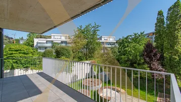 Geräumiger Balkon mit Fliesenboden und Blick auf die umliegenden Gebäude und Grünflächen.