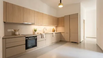 Moderne Einbauküche in Beige mit integrierten Geräten und hellem Boden.